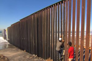 man attempting to climb border wall